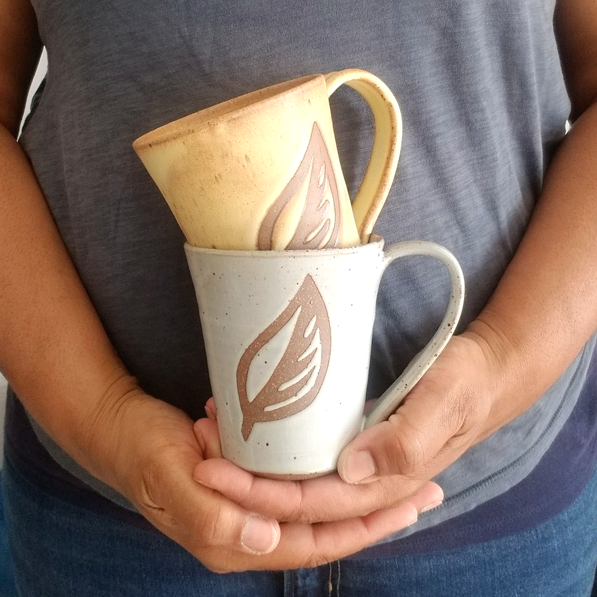 Nathalie Royston Holding one yellow and one white ceramic mug