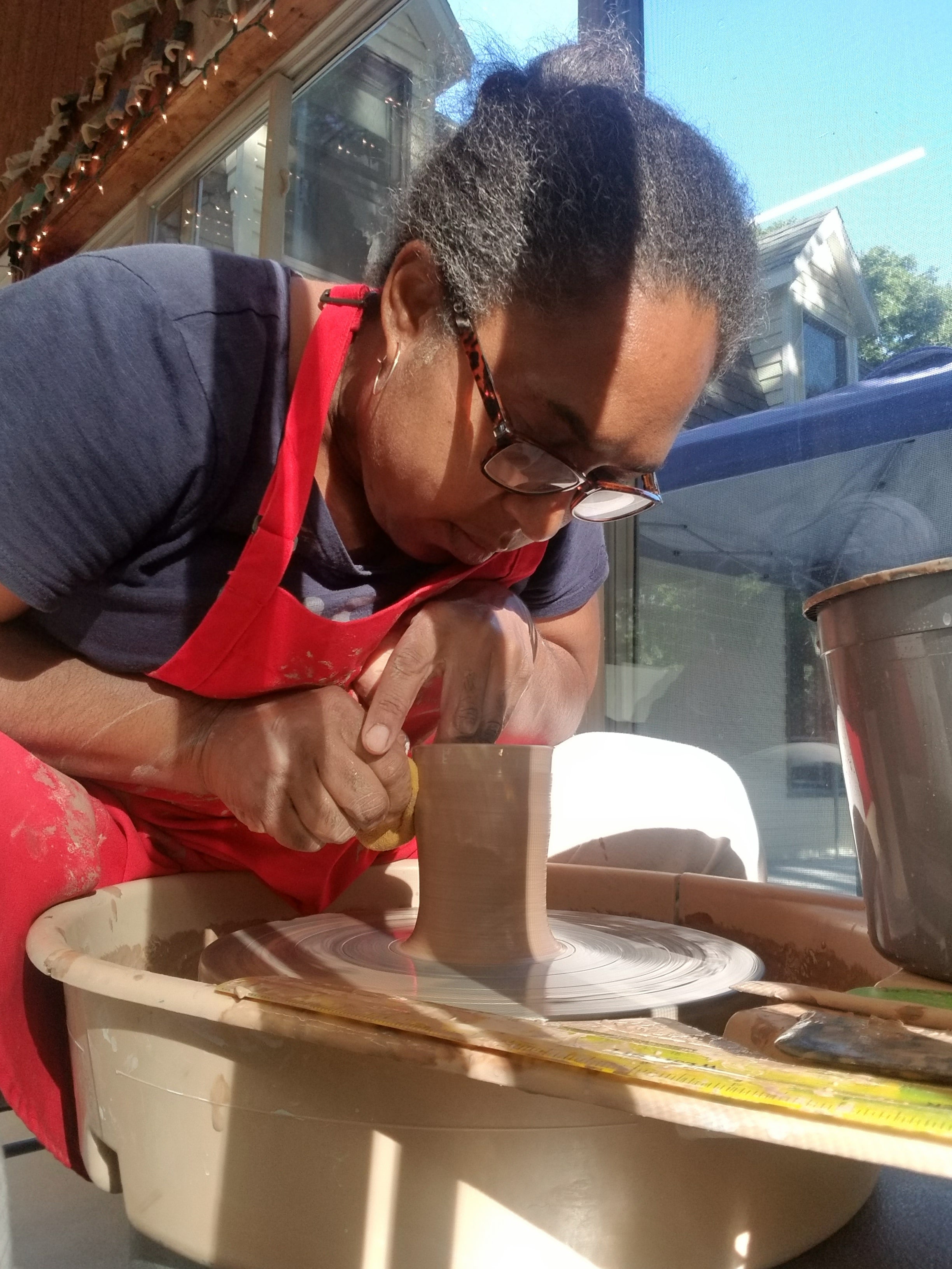 Photo of Nathalie Royston throwing a ceramic cylinder on the wheel