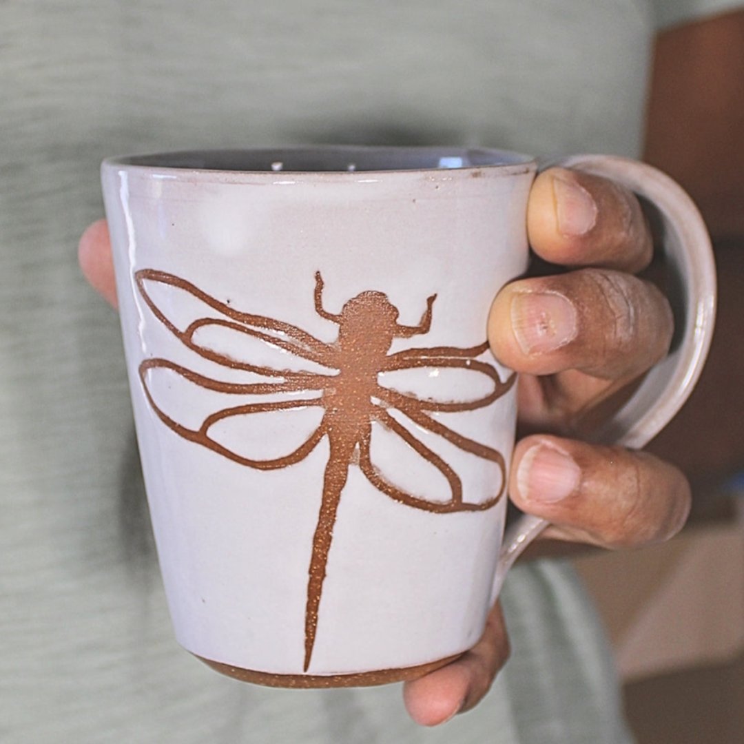 White ceramic mug with dragonfly stencil in hand