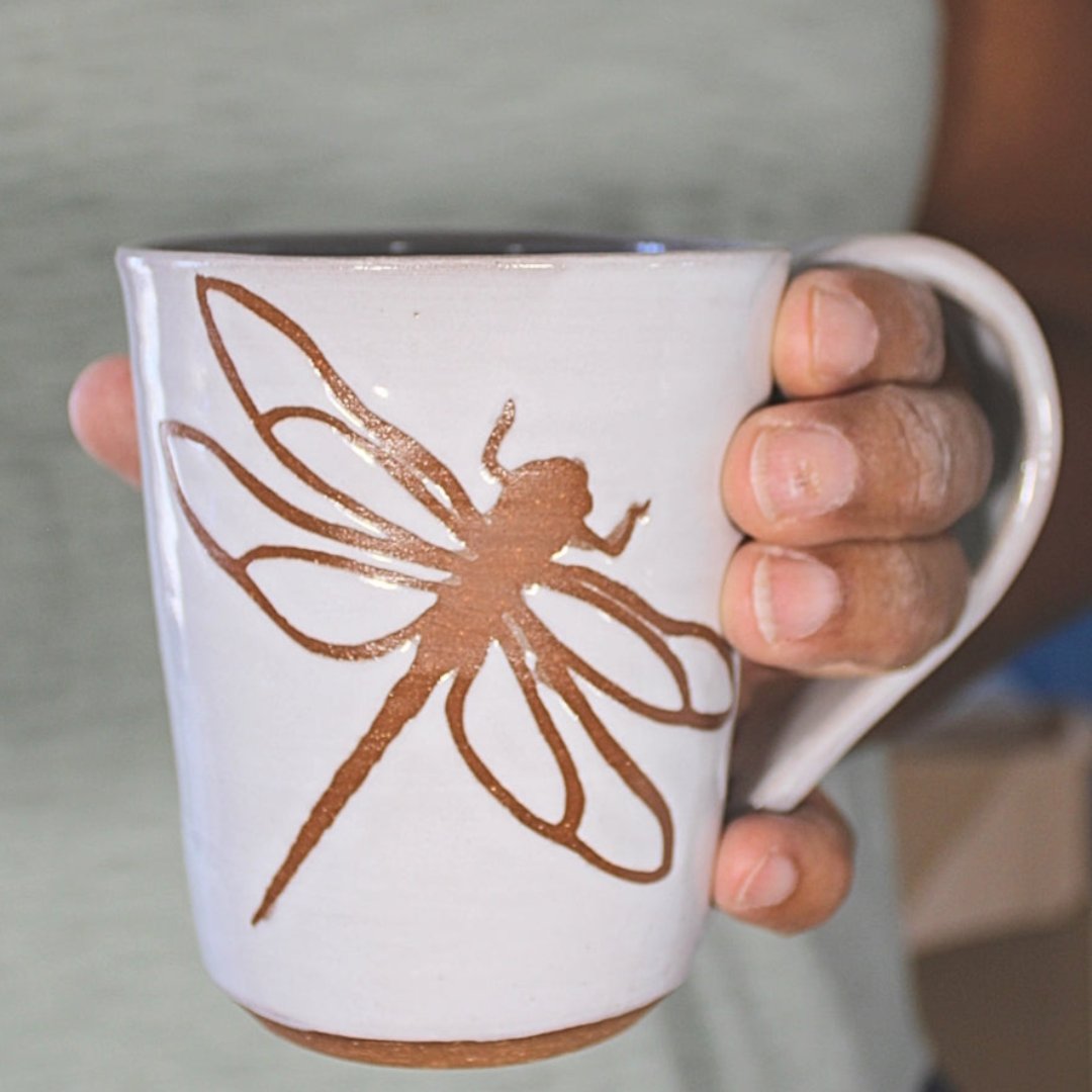 White ceramic mug with dragonfly stencil in hand