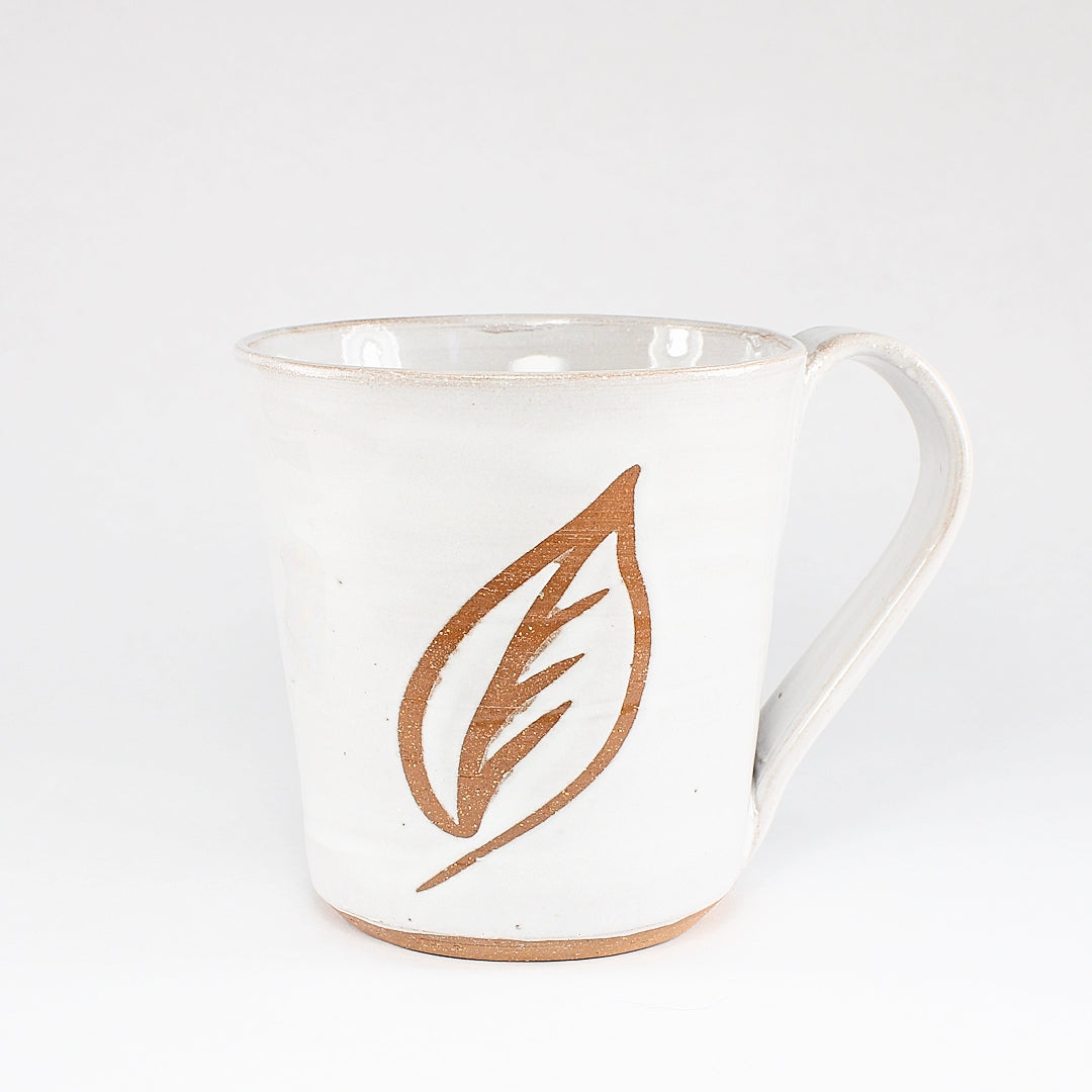 White ceramic mug with leaf stencil