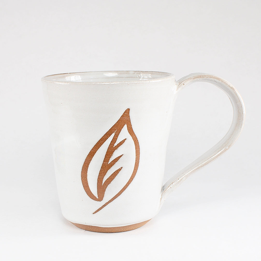 White ceramic mug with leaf stencil