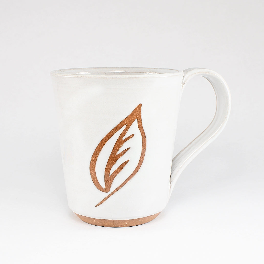 White ceramic mug with leaf stencil