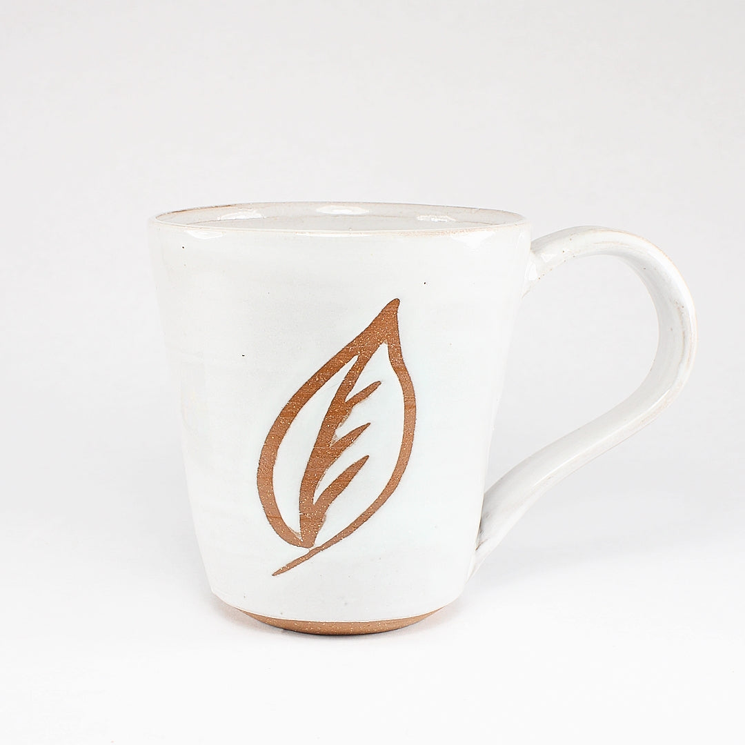 White ceramic mug with leaf stencil