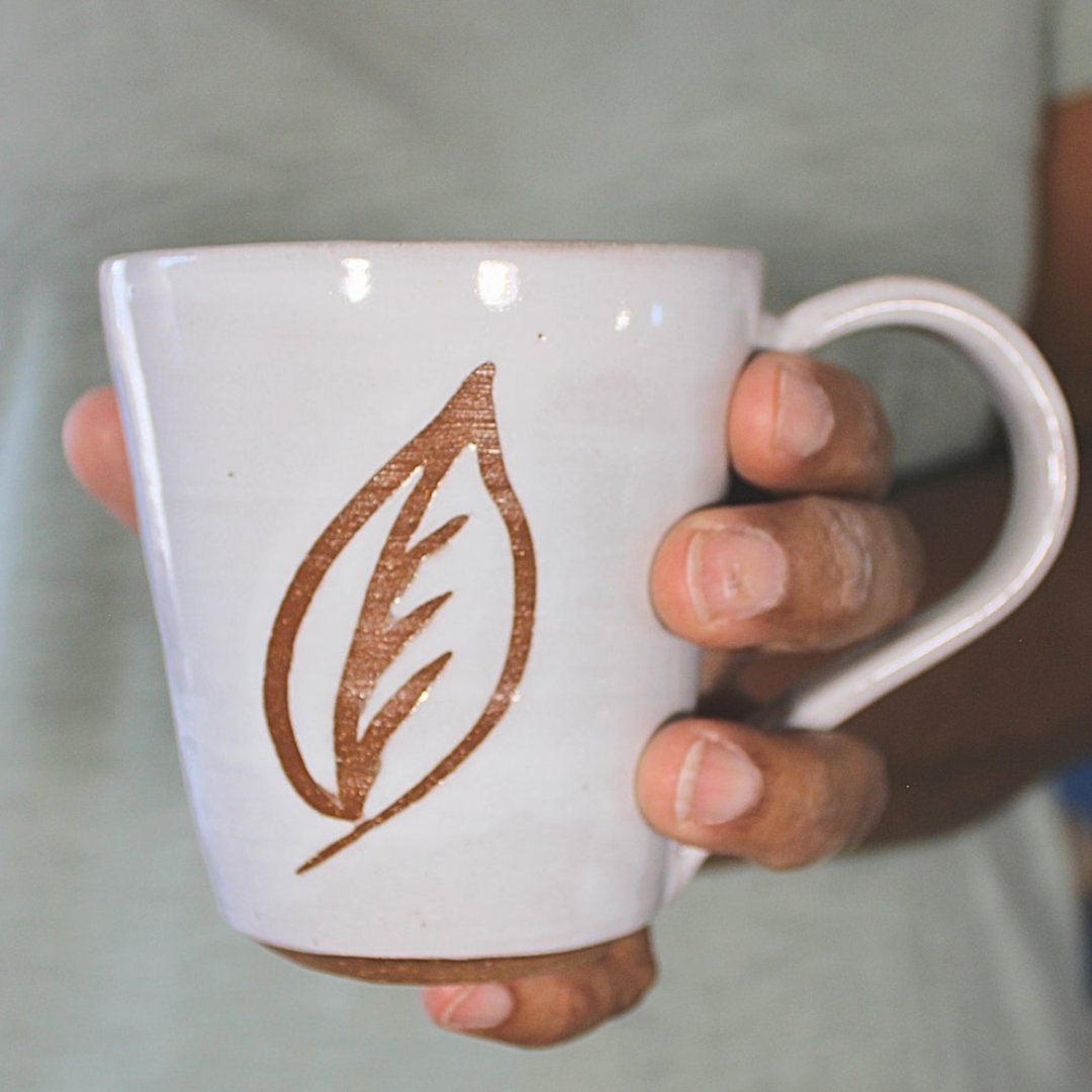 White ceramic mug with leaf stencil  in hand