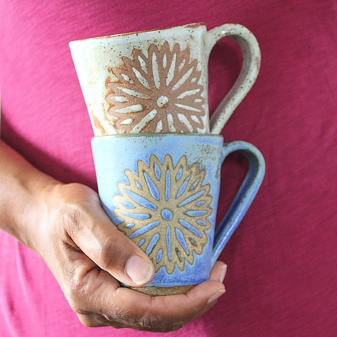 Nathalie Royston holding one blue and one white handmade ceramic flower mug